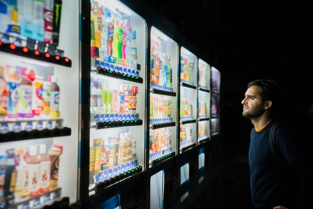 Confused man looking at vending machine options